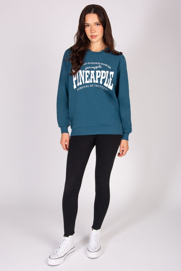 Woman wearing a blue sweatshirt with text, black leggings, and white sneakers on a white background
