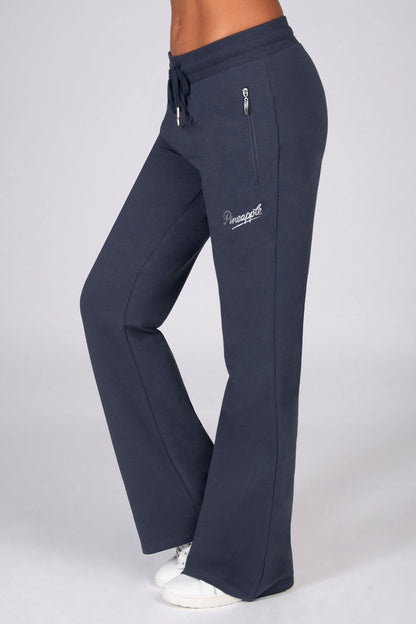 Dark grey flared trousers with zip pockets worn by a person on a light grey background.