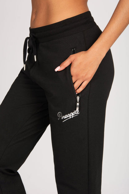 Black pants with a brand logo, zip pockets and drawcord waistband on a plain background