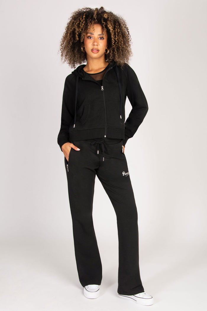 Woman wearing a black tracksuit with zip zip pockets on a white background