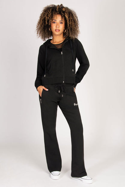 Woman wearing a black tracksuit with zip zip pockets on a white background