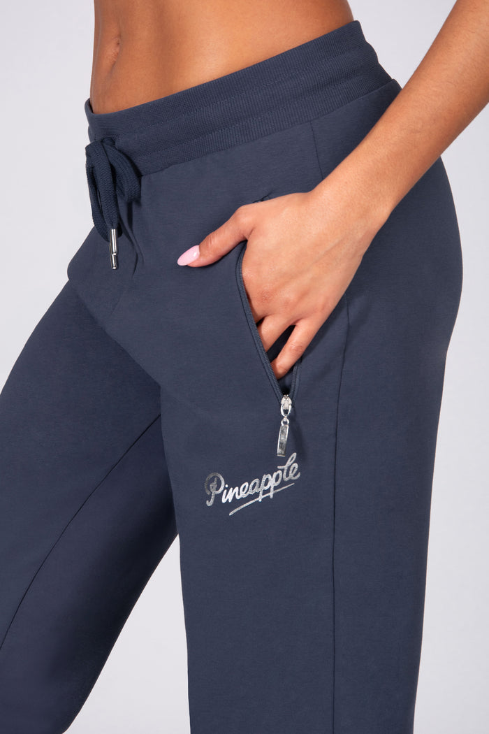 Women's dark grey flared trousers with zip pockets on a light grey background.