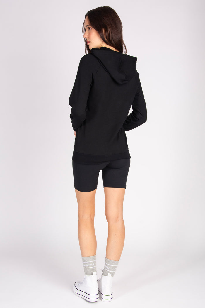 Woman wearing a black hoodie and shorts on a white background