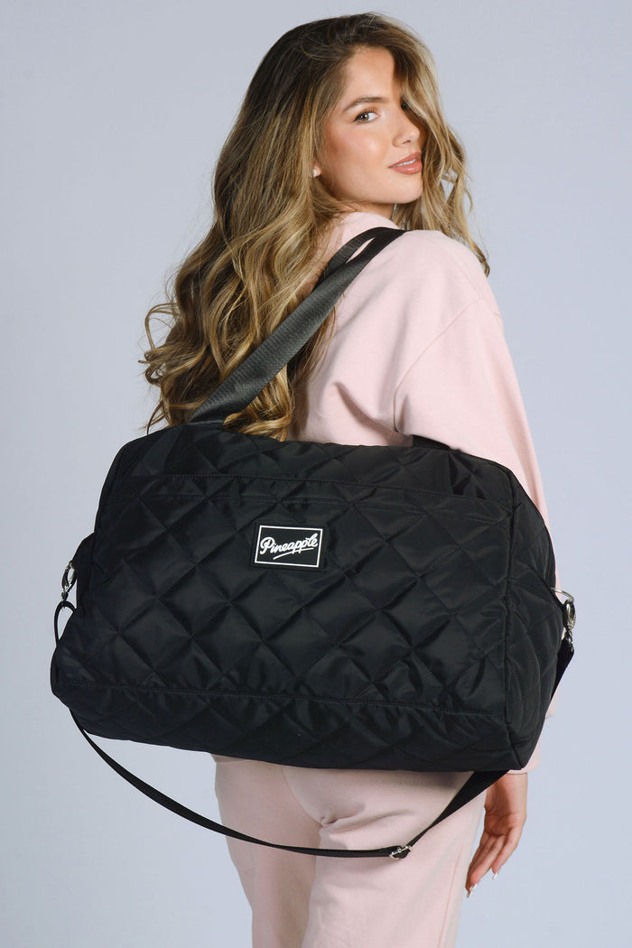 Woman carrying black Quilted Holdall Bag