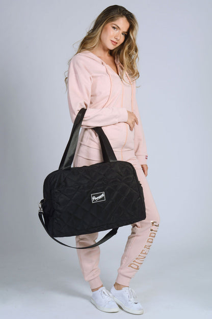 Woman carrying black Quilted Holdall Bag with logo badge