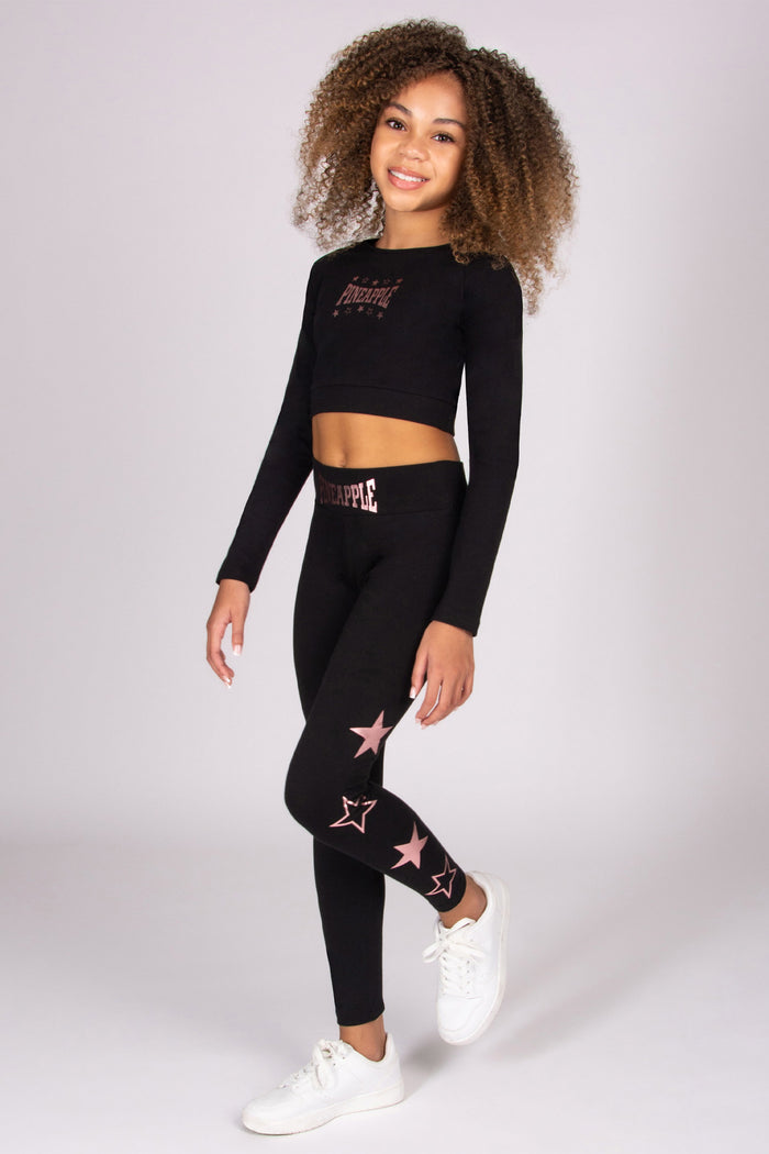 Person wearing a black long-sleeve top and leggings with star patterns on a white background
