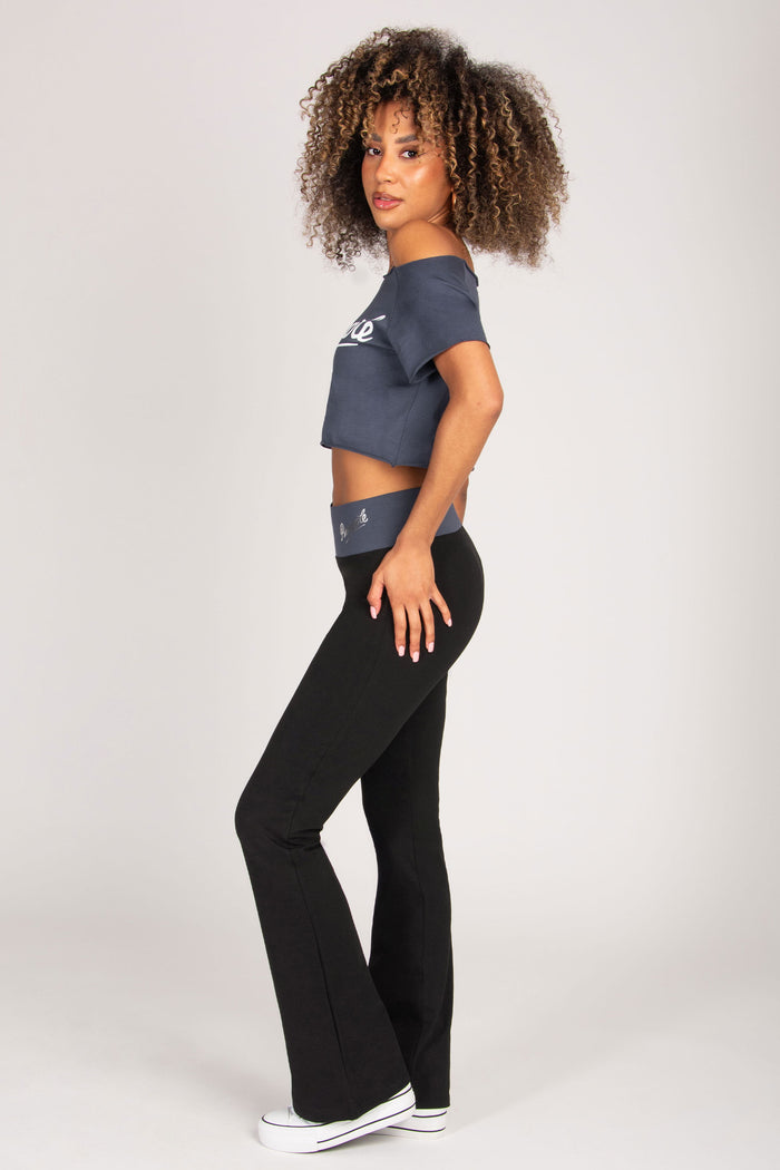 Woman wearing a dark grey crop top and black leggings on a white background