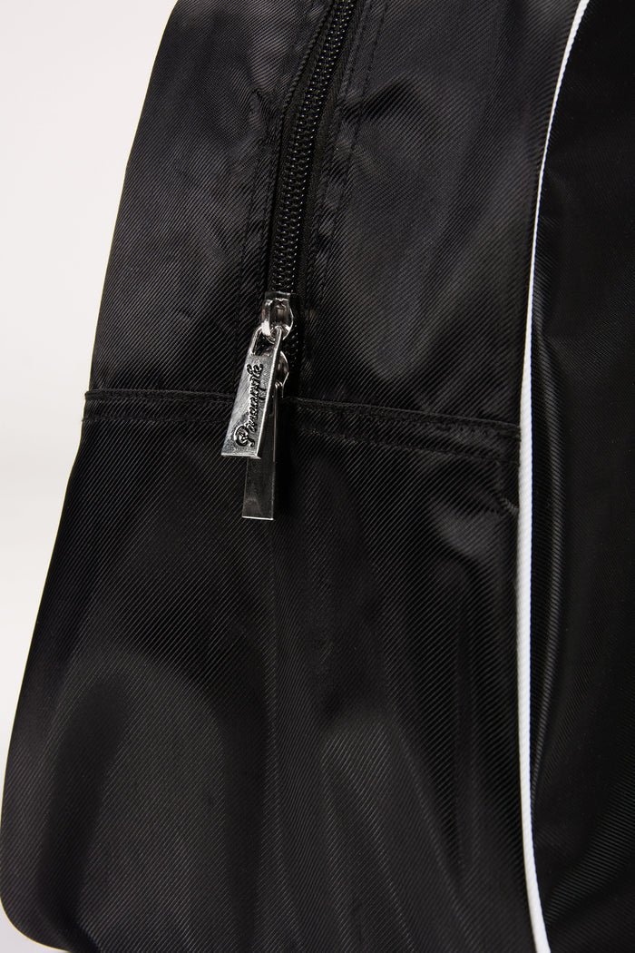 Close-up of a black bag with a zipper and brand tag on a white background