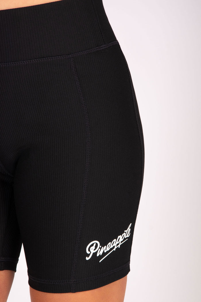 Black rib cycling shorts with elasticed waistband and small white branding on the left leg.