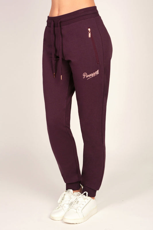 Women's slim fit joggers with zip pockets and drawcord waistband on a plain background.