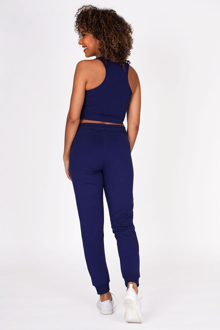 Woman wearing Navy Skinny Zip Trousers and navy racer midi crop top, back view