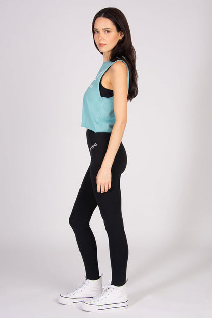Woman wearing a light blue sleeveless top and black leggings on a white background