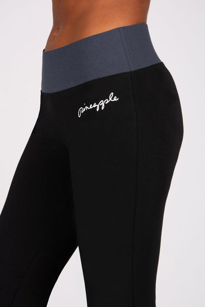 Black flared leggings with a charcoal grey waistband featuring a brand logo on a white background