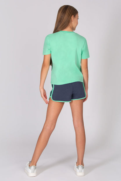 Teenager wearing a light blue t-shirt and dark grey shorts on a white background
