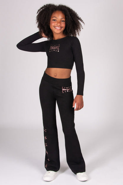 Girl wearing a black long-sleeve top and black flared trousers with rose gold print on a white background