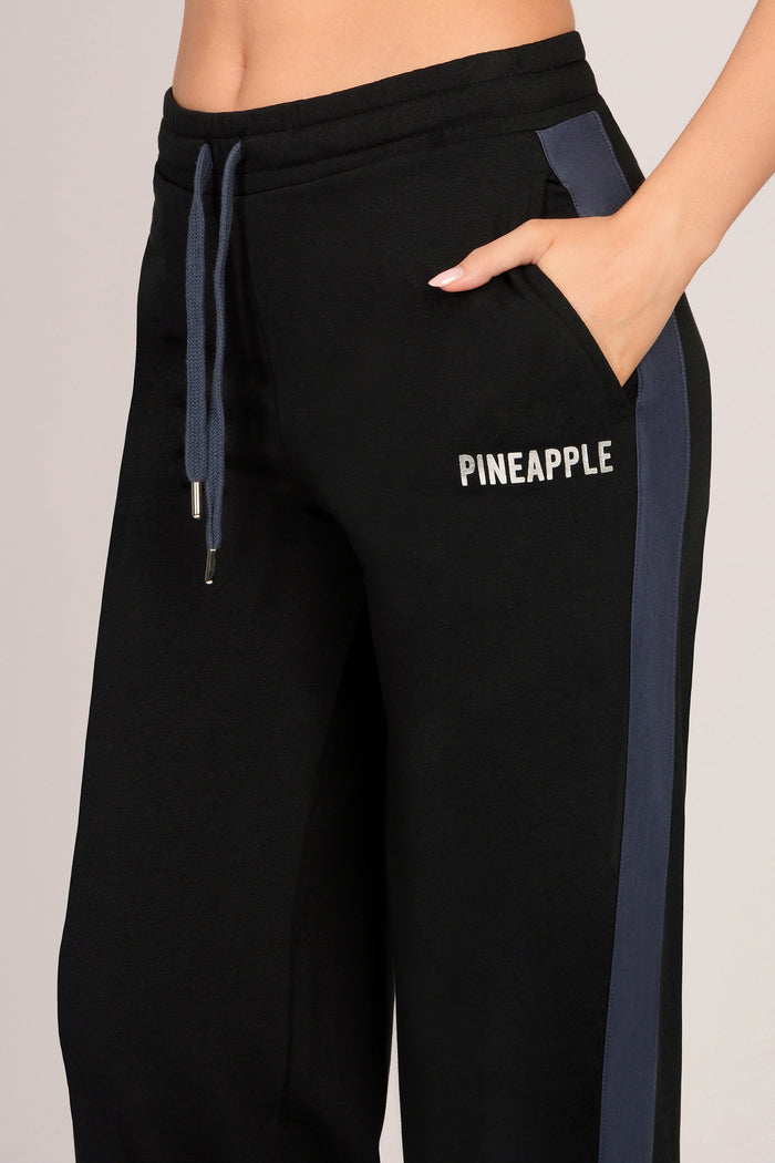 Black pocket jogger pants with 'PINEAPPLE' branding on a light grey background