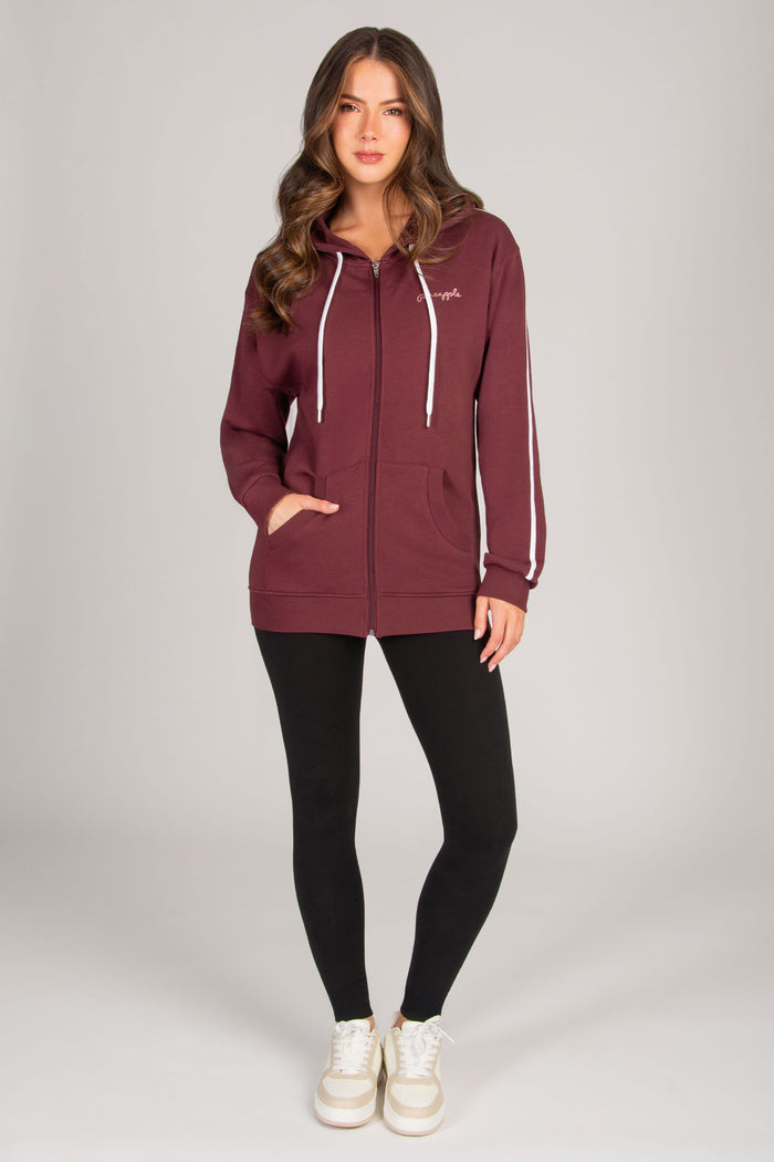 Kianna Louise wearing a burgundy zip hoodie with pockets and white panelling along the sleeves on a grey background