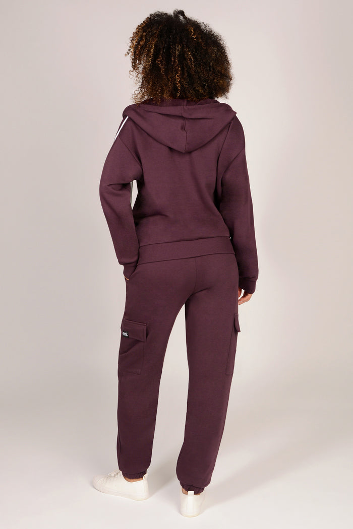 Person wearing a maroon tracksuit on a white background
