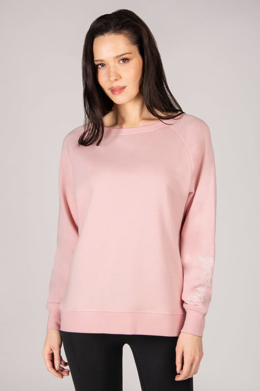 Woman wearing a pink sweater against a plain background