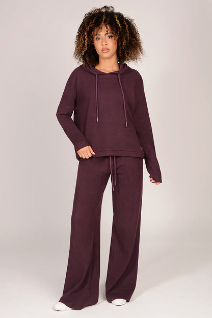 Woman wearing a maroon tracksuit on a white background