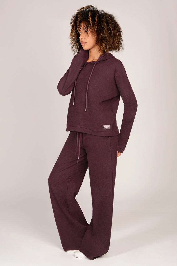 Woman wearing a maroon tracksuit on a white background
