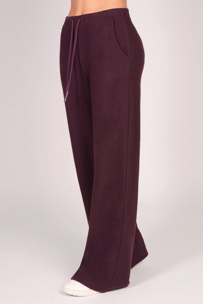 Women's maroon brown wide leg trousers with pockets and drawcord on a plain background.