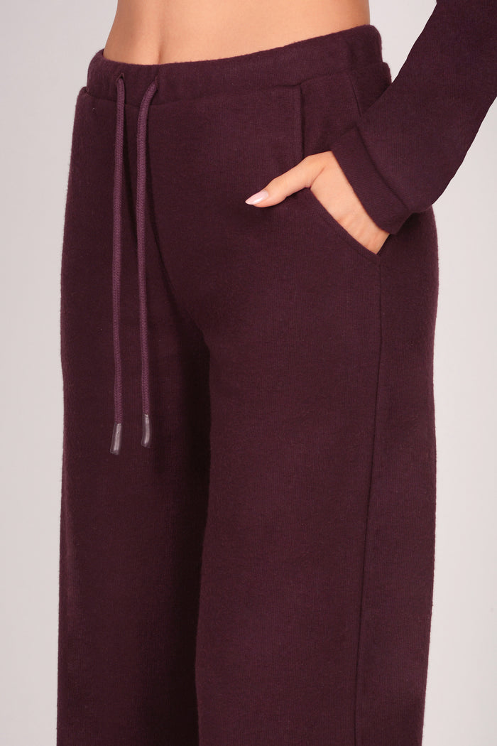 Detail shot of women's maroon brown pocket trousers on a plain background.