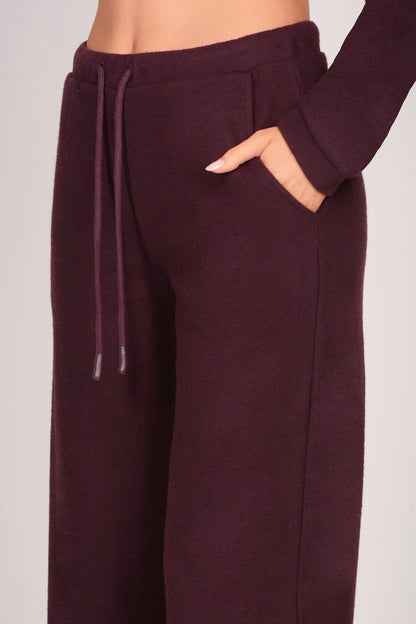 Detail shot of women's maroon brown pocket trousers on a plain background.