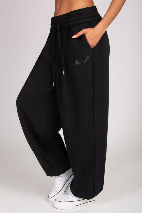 Close up of ultra oversized black joggers featuring side pockets.