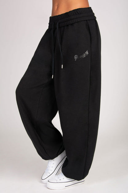 Detailed view of extra baggy black joggers with spacious pockets.
