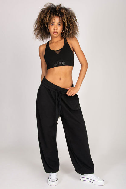 Woman wearing black super oversized joggers with pockets paired with mesh sports bra.