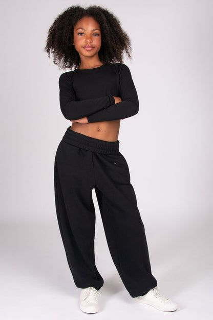 Girl wearing a black joggers with roll-down waistband on a white background
