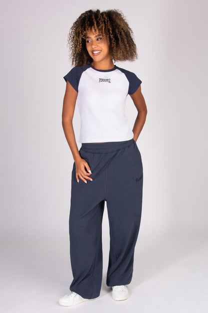 Woman wearing a white and navy baseball  t-shirt with navy joggers on a white background