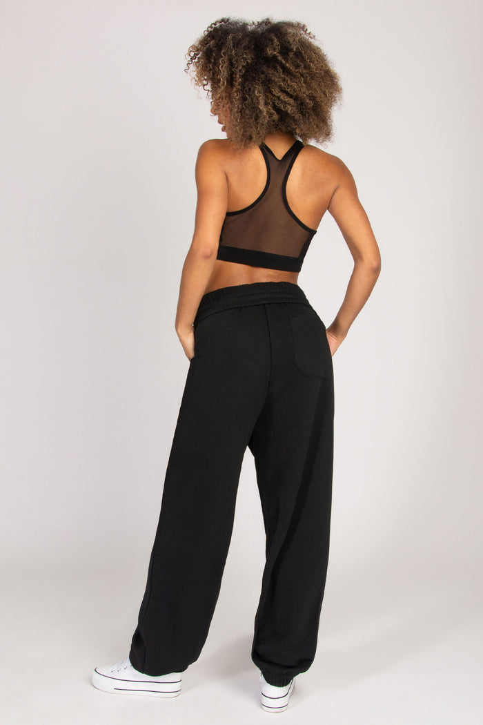Model wearing balloon fit black joggers with functional side pockets and a right back pocket, paired with a mesh performance bra.