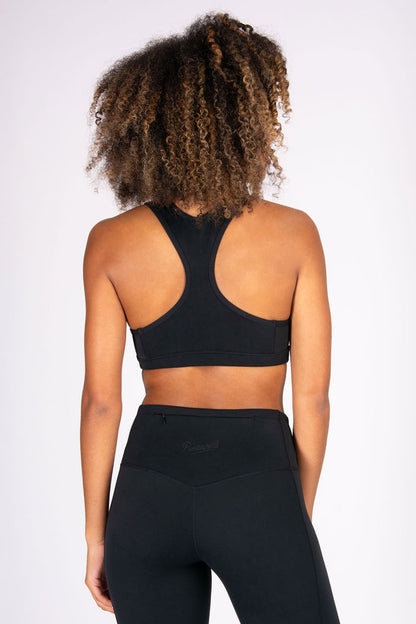 Woman wearing a black sports bra and leggings with hidden zip pocket on a white background