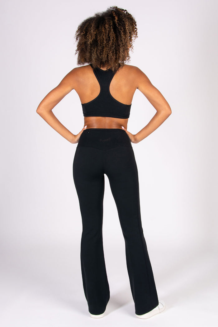 Person wearing a black racer back sports bra and super soft flared leggings on a white background