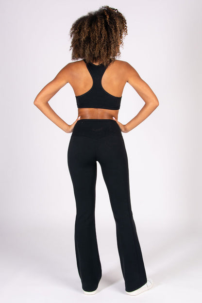 Person wearing a black racer back sports bra and super soft flared leggings on a white background