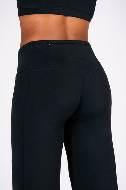 Black yoga trousers with hidden zip pocket worn by a person.