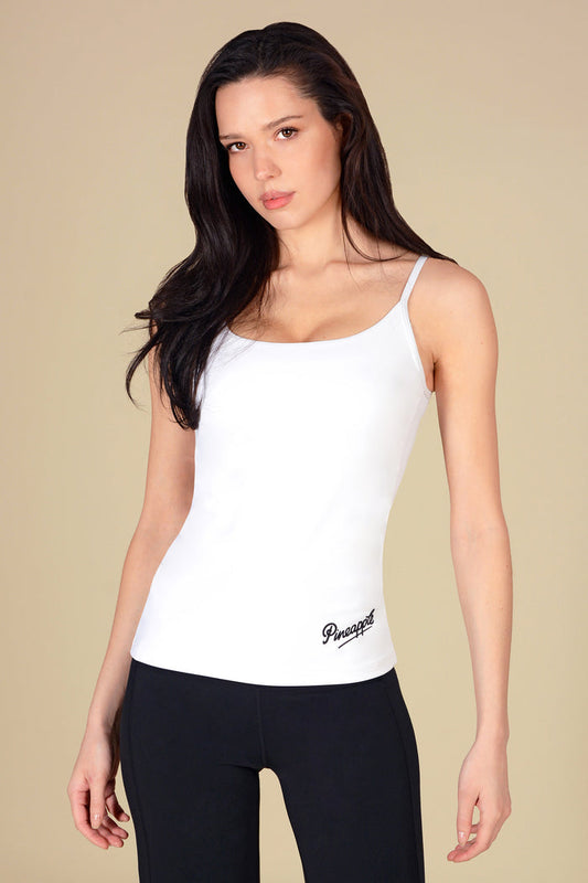 Woman wearing a basic white tank top on a beige background