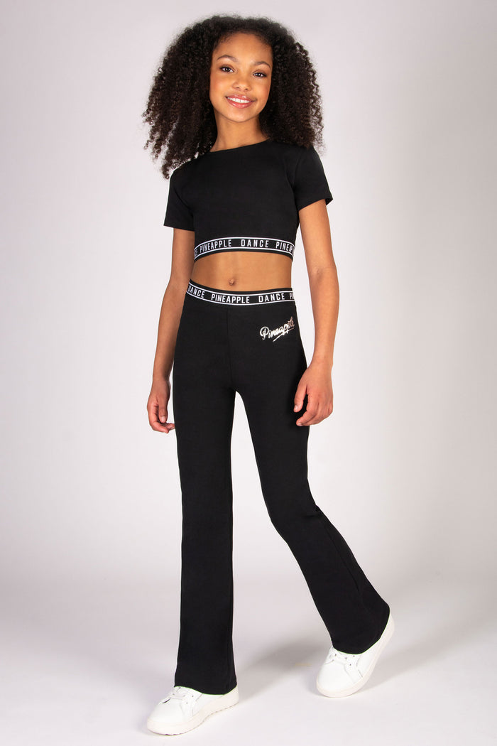 Girl wearing black crop top with short sleeves and elasticated waistband