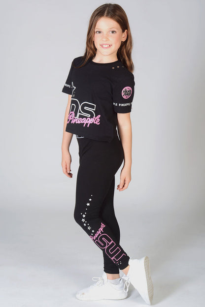 Young dancer wearing matching The Next Step dancewear featuring TNS logo crop black t-shirt and Pineapple leggings with silver star details.
