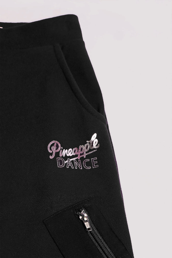 Detail of Pineapple Dance hip logo and zip pocket of black wide leg cargo joggers for girls.